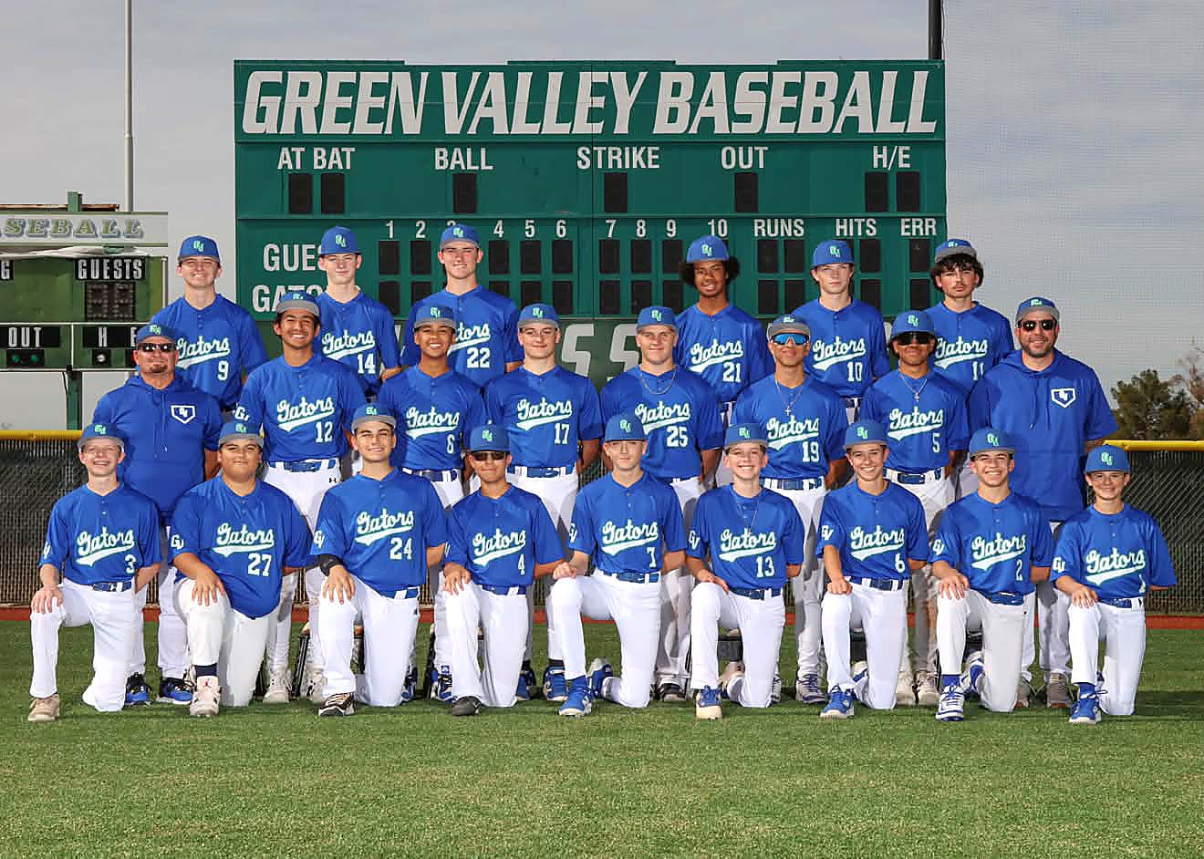 Green Valley Gators junior varsity team photograph in blue Gators jerseys, white pants and caps, posed in three rows on the field in front of the Green Valley Baseball scoreboard